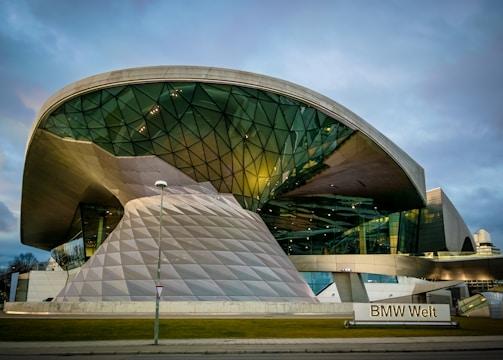 A futuristic building with a large, curved glass and metal structure, featuring geometric patterns and reflective surfaces. The architecture is innovative and modern, with clean lines and an expansive shape.